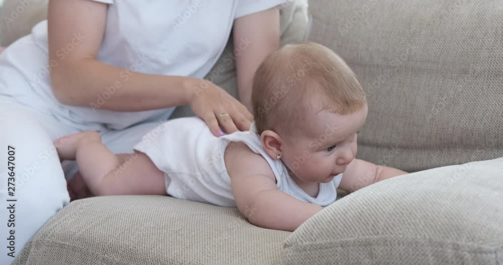 Mother stroking her cute baby daughter on sofa at home Mother stroking her cute baby daughter on sofa at home