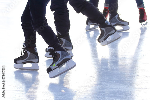 feet of different people skating on the ice rink