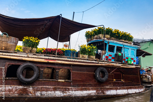 Canvastavla Brown and blue boat or sampan carrying yellow and red flowers for Tet New Year Celebration, Mekong Delta, Vietnam