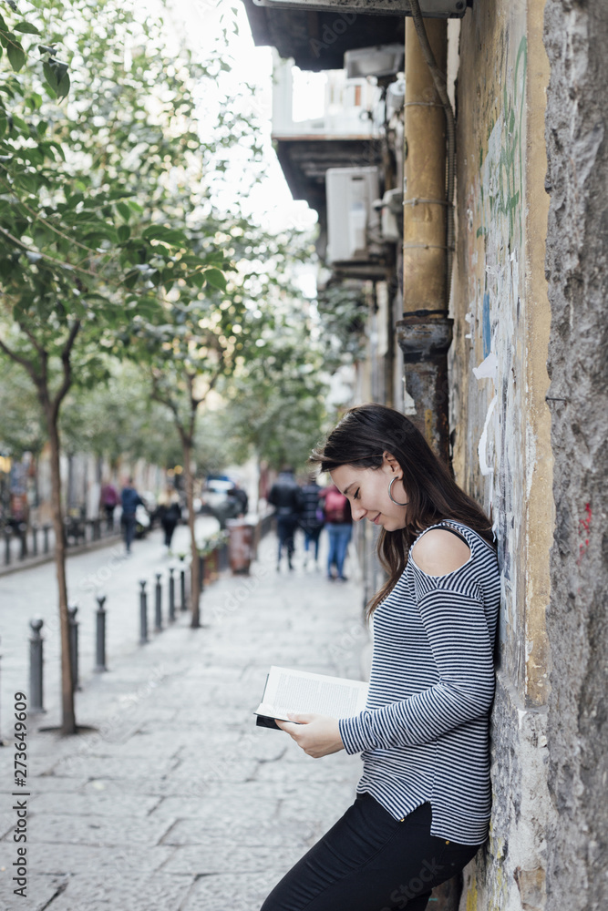 Girl reading a book in the street