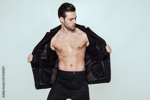 Muscle strong beautiful stripped male model in black toxedo and black trousers on grey isolated font background photo