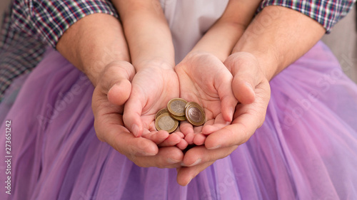 Dad and his daughter holding coins in hands together