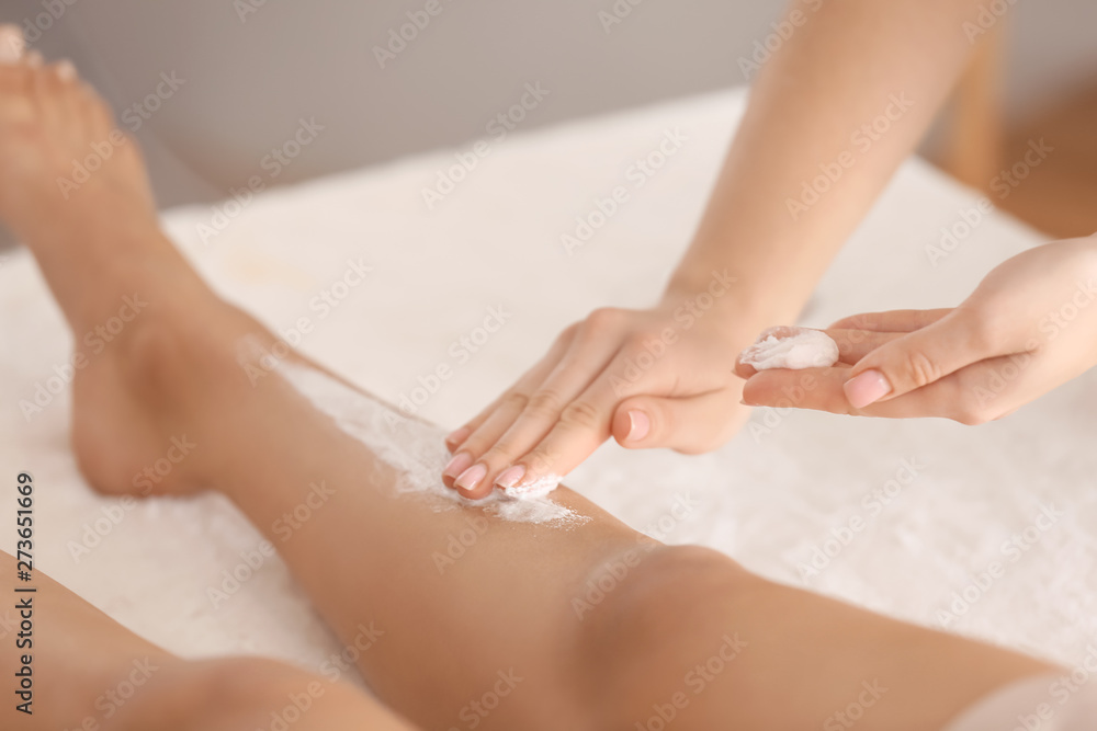 Fototapeta premium Young woman undergoing treatment with body scrub in spa salon