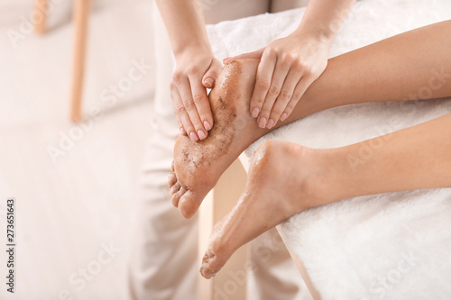 Young woman undergoing treatment with body scrub in spa salon