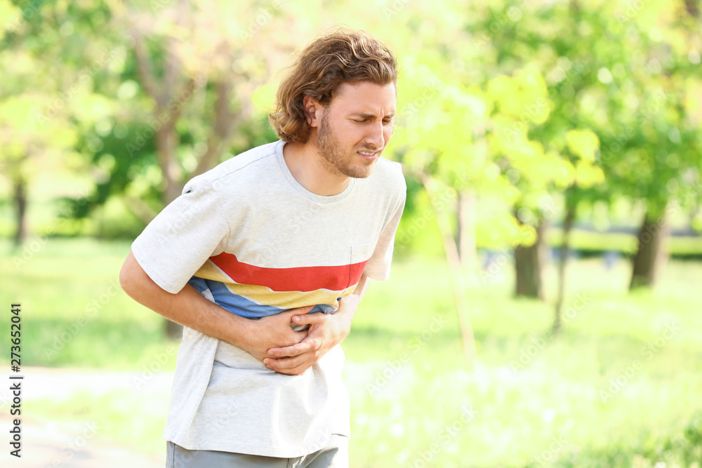 Young man suffering from stomachache outdoors Young man suffering from stomachache outdoors