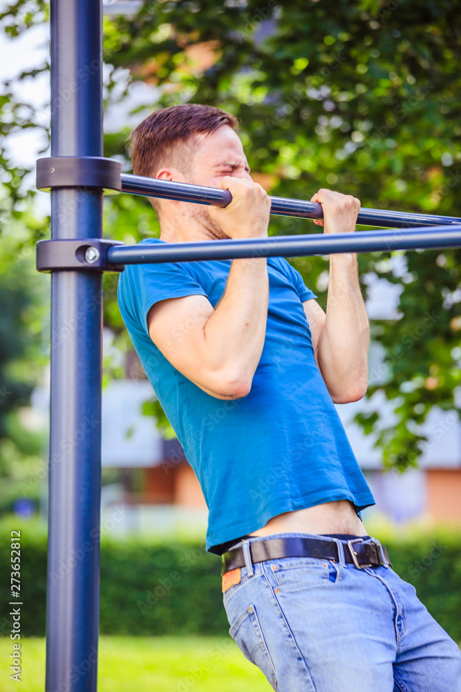 Workout in summer: Young fit Caucasian man is doing pull ups Workout in summer: Young fit Caucasian man is doing pull ups