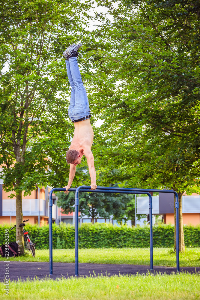Workout in summer: Young fit Caucasian man is doing a handstand
