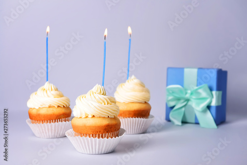 Tasty Birthday cupcakes with gift box on grey background