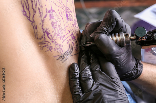 Professional artist making tattoo in salon, closeup