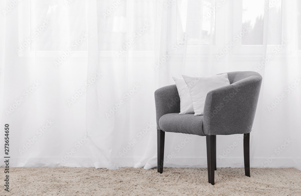 Armchair with soft pillows near window in living room Armchair with soft pillows near window in living room