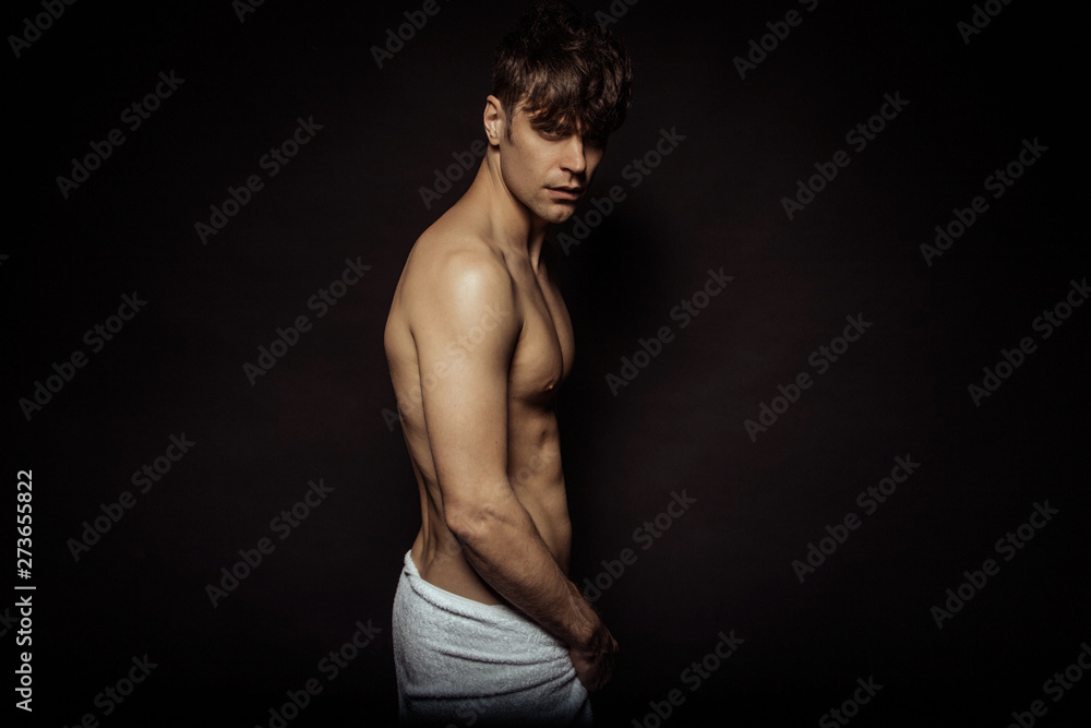 Strong stripped muscle male model with white towel on black isolated font background