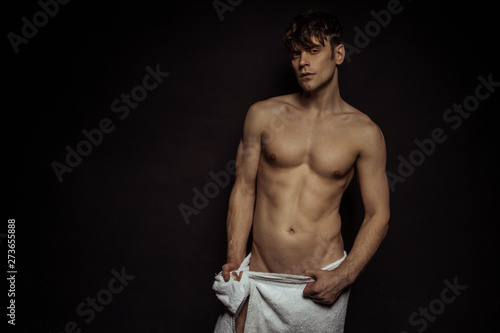 Foto Strong stripped muscle male model with white towel on black isolated font backgr