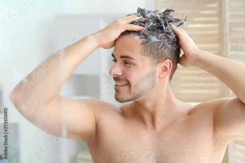 Handsome man washing hair i...