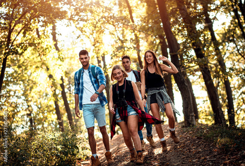 Group of four friends having fun hiking through forest together.