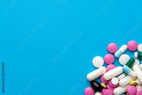Flat lay - multicolored pills, drugs and capsules on blue background