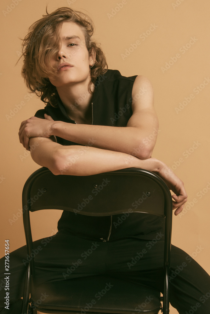 Muscle blonde beautiful stripped male model with long hair in black casual  look on beige brown isolated font background Stock Photo | Adobe Stock