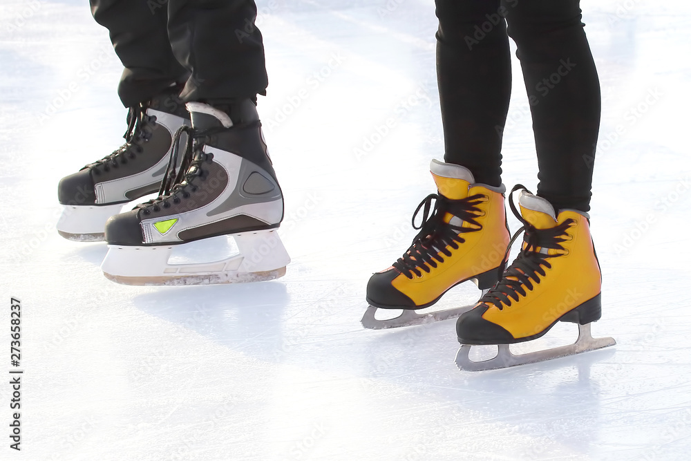 Fototapeta premium feet of different people skating on the ice rink