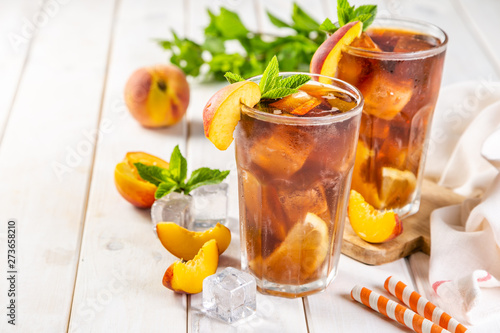 Iced tea and ingredients in glasses on wood background, copy space