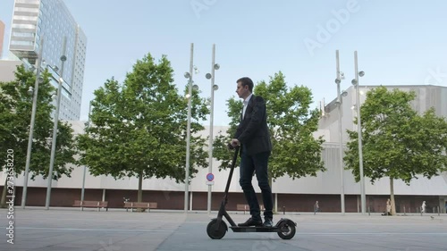 Young businessman riding an electric scooter for a business meeting in the office, office buildings, business man, sunset, electric transport, ecological transport, 4k, e-skateboard