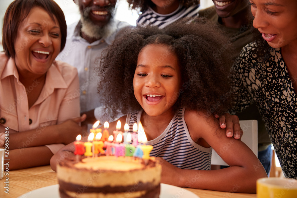 Obraz premium Multi-Generation Family Celebrating Granddaughters Birthday At Home With Cake And Candles