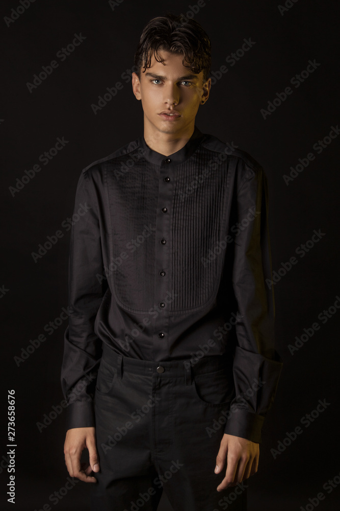 Strong stripped muscle male model in formal look with black shirt and black trousers on black isolated font background Strong stripped muscle male model in formal look with black shirt and black trousers on black isolated font background