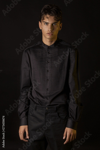 Strong stripped muscle male model in formal look with black shirt and black trousers  on black isolated font background © Oleh Phoenix