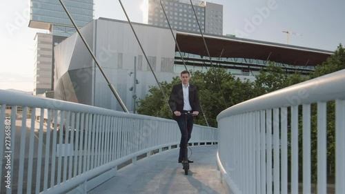Young businessman riding an electric scooter for a business meeting in the office, office buildings, business man, sunset, electric transport, ecological transport, 4k, e-skateboard
