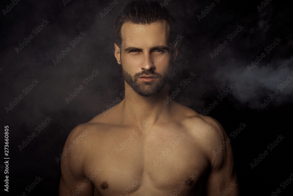 Handsome sport sexy stripped guy portrait in a water draps and fog smoke mist on isolated black background Handsome sport sexy stripped guy portrait in a water draps and fog smoke mist on isolated black background