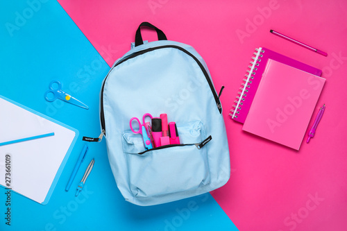 School backpack with stationery on color background