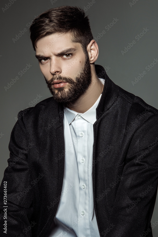 Fototapeta premium Muscle strong bearded face beautiful stripped male model in formal look with shirt and suit on grey isolated font background