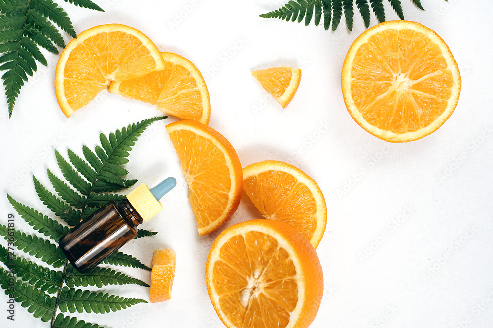 Natural cosmetic skincare serum packaging with leaf fern and fresh juicy  orange fruit on white background. Beauty vitamin ingredient. alternative  medicine. Flat lay, top view, copy space Stock Photo