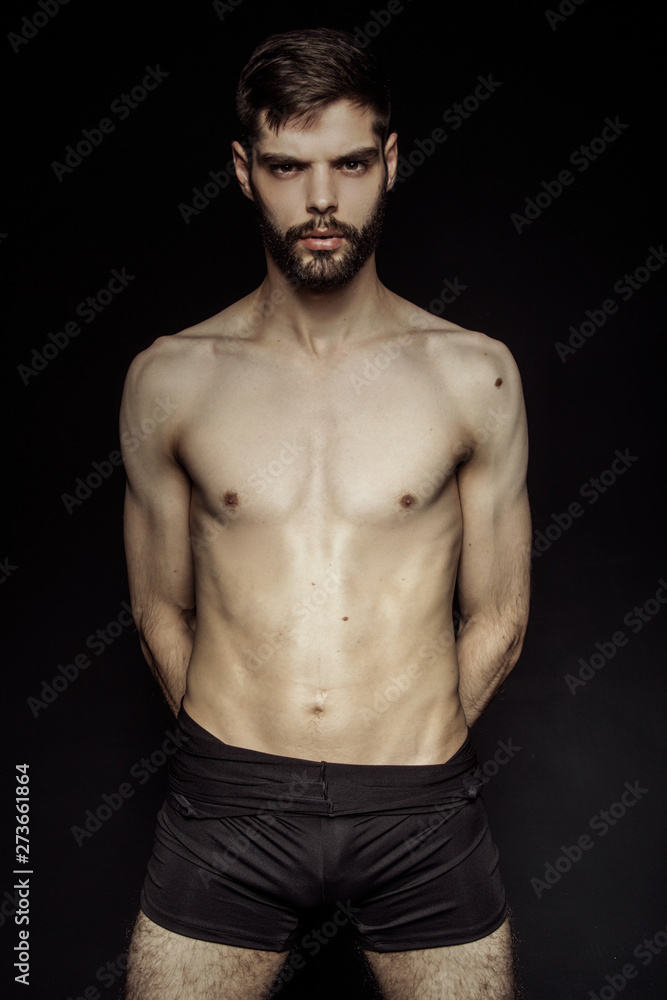 Muscle strong bearded face beautiful stripped male model in black underwear on black isolated font background