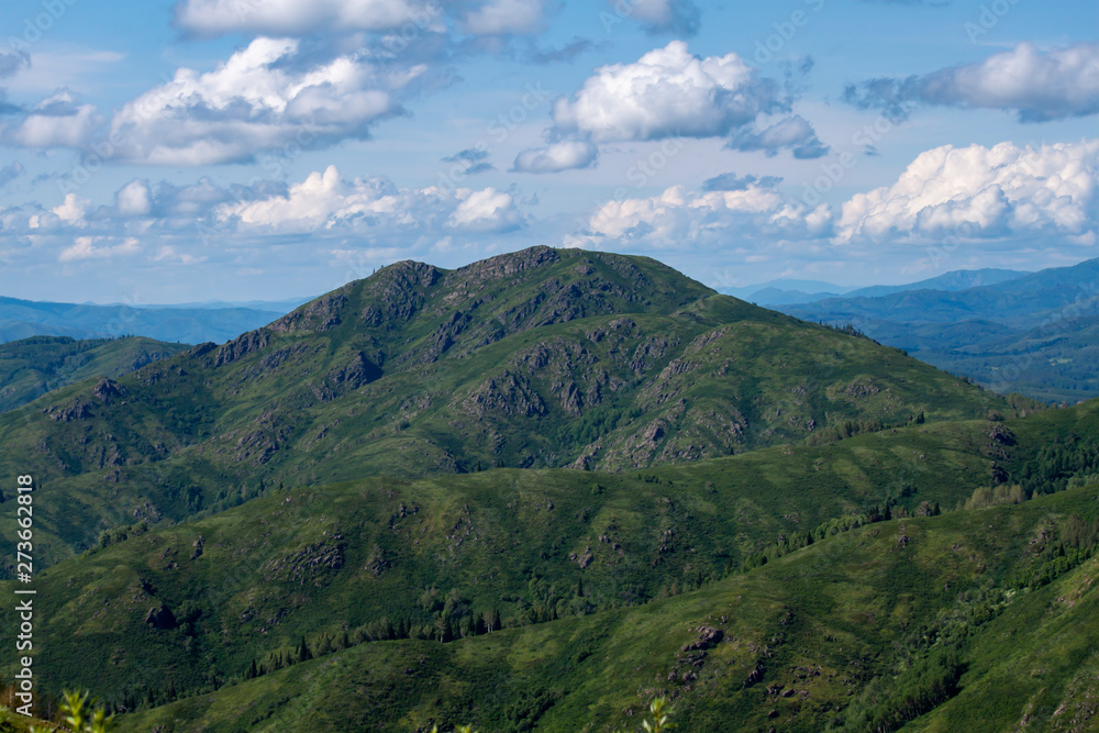 Fototapeta premium Natural landscape. Beautiful cumulus clouds float above a mountain valley.
