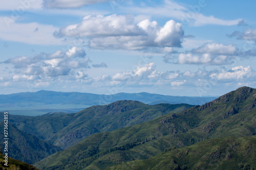 Natural landscape. Beautiful cumulus clouds float above a mountain valley.