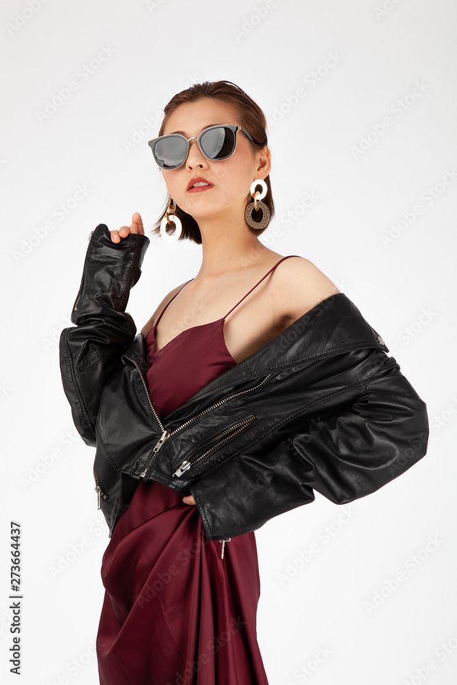 Asian Chinese Fashion influencer modeling in a wine color silk dress and leather jacket isolated in white background Asian Chinese Fashion influencer modeling in a wine color silk dress and leather jacket isolated in white background