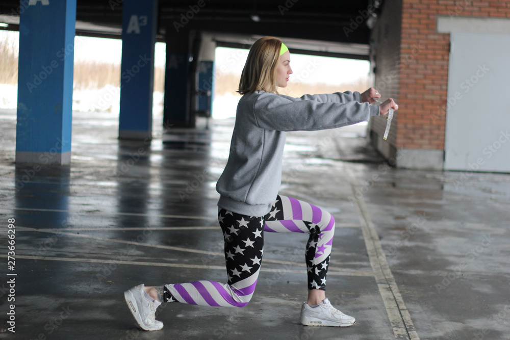 Obraz premium Girl is a blonde trainer in a gray thin. Street style. Advertising brand clothing. Fashion Shooting. Sentimental strip for swirling volume. Shopping cart in supermarket.