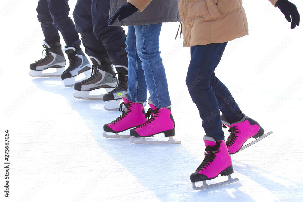 feet of different people skating on the ice rink feet of different people skating on the ice rink