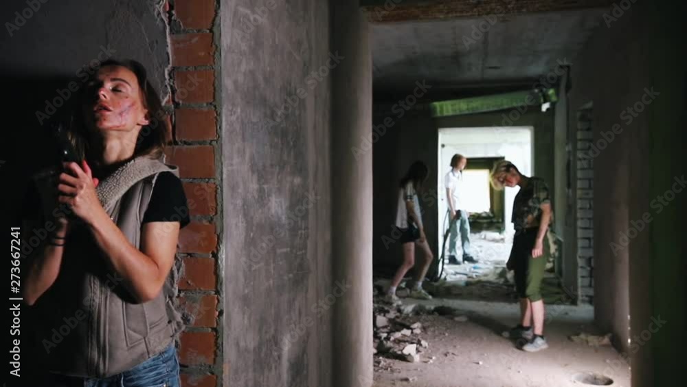 A zombie apocalypse. Survived woman with a gun hiding behind a wall and ...