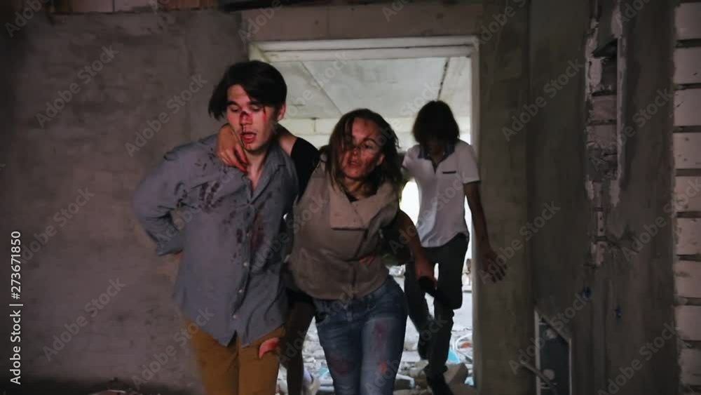 Tired survivors holding by each other and escaping from the zombies in the abandoned building Tired survivors holding by each other and escaping from the zombies in the abandoned building