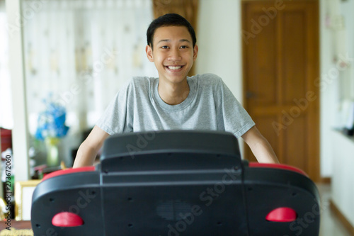 Healthy asian men smiling with happy face while standing on a running machine at home.
