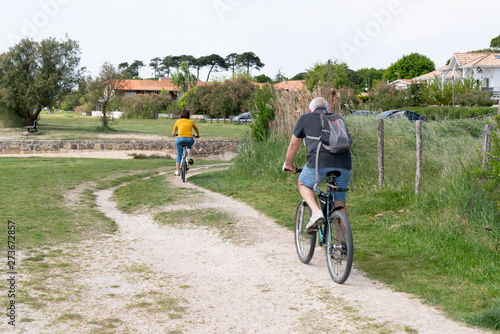 Papier peint Rear View Of  Couple biking Cycling On Country Lane