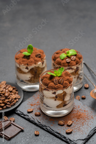 Classic tiramisu dessert in a glass on stone serving board on dark concrete background