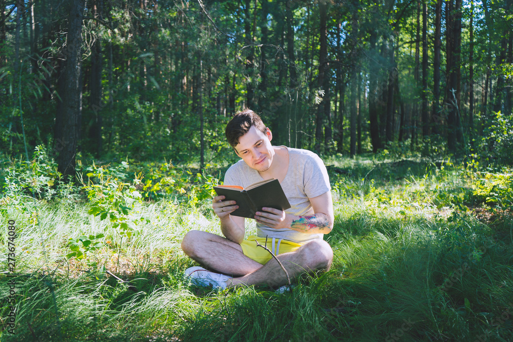 Young handsome man reading book in open space