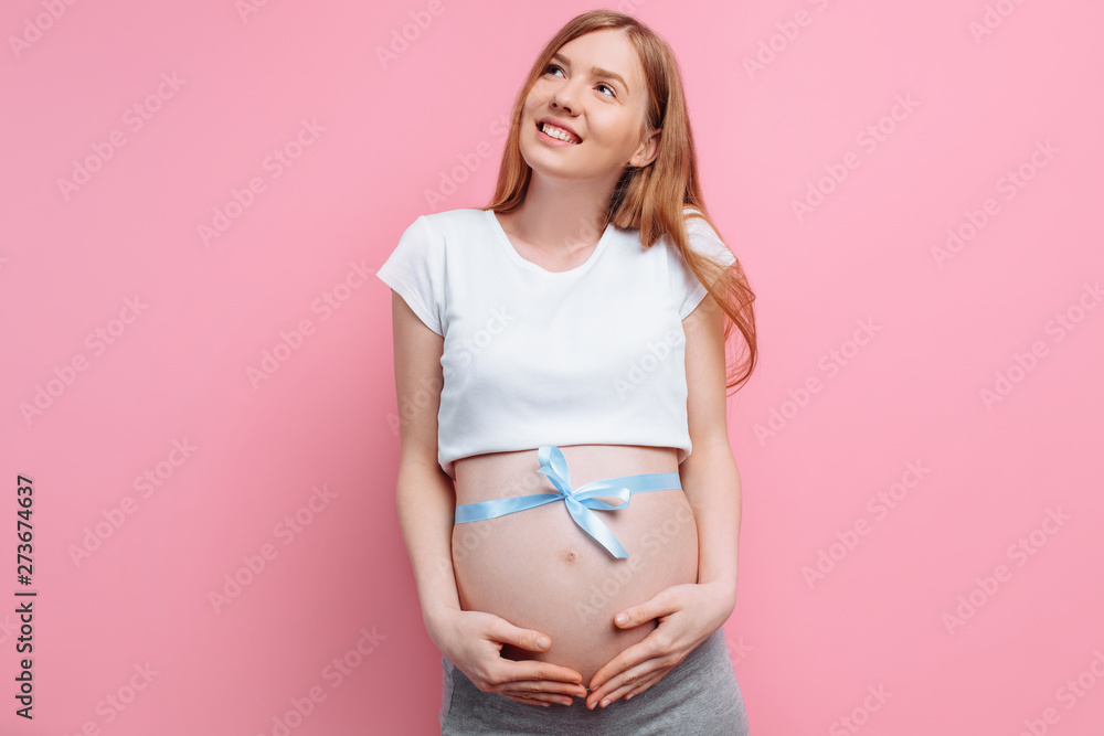 An image of a pregnant happy woman with a blue ribbon on her belly An image of a pregnant happy woman with a blue ribbon on her belly
