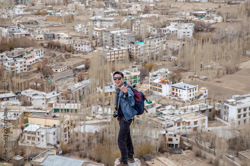 Traveler man standing on Leh Ladakh city view from Shanti Stupa. Beautiful amazing village in the valley with snow mountain at background. Ladakh, India. photo