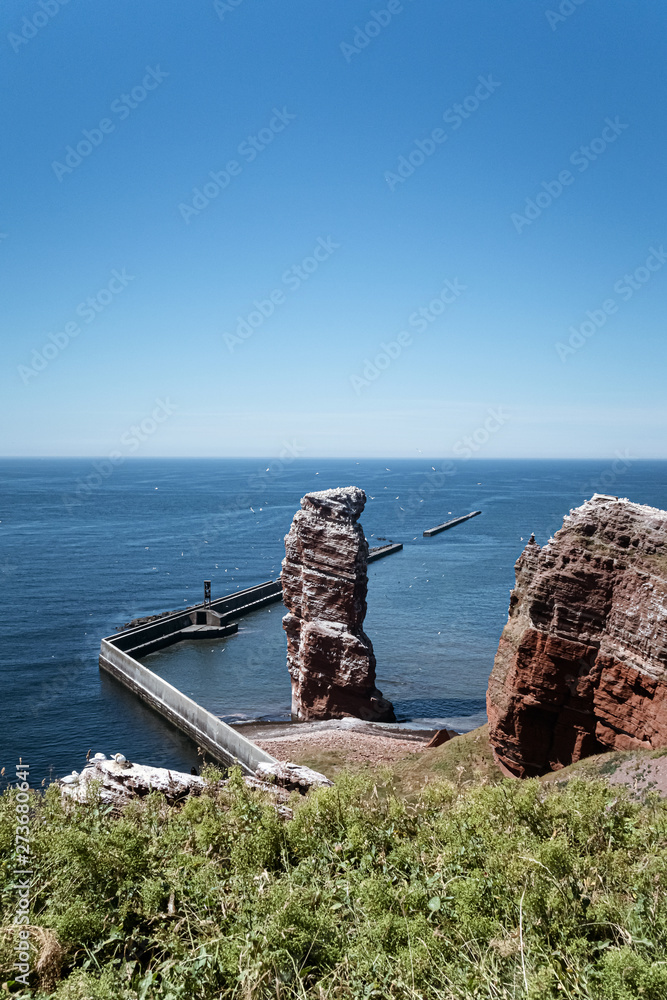 high sea stack Lange Anna on Heligoland island, Germany surrounded by flying birds on sunny summer day