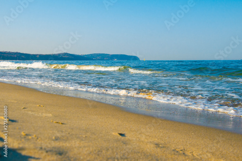 Sea, sandy beach and rocky shore on the horizon. © Alisandra