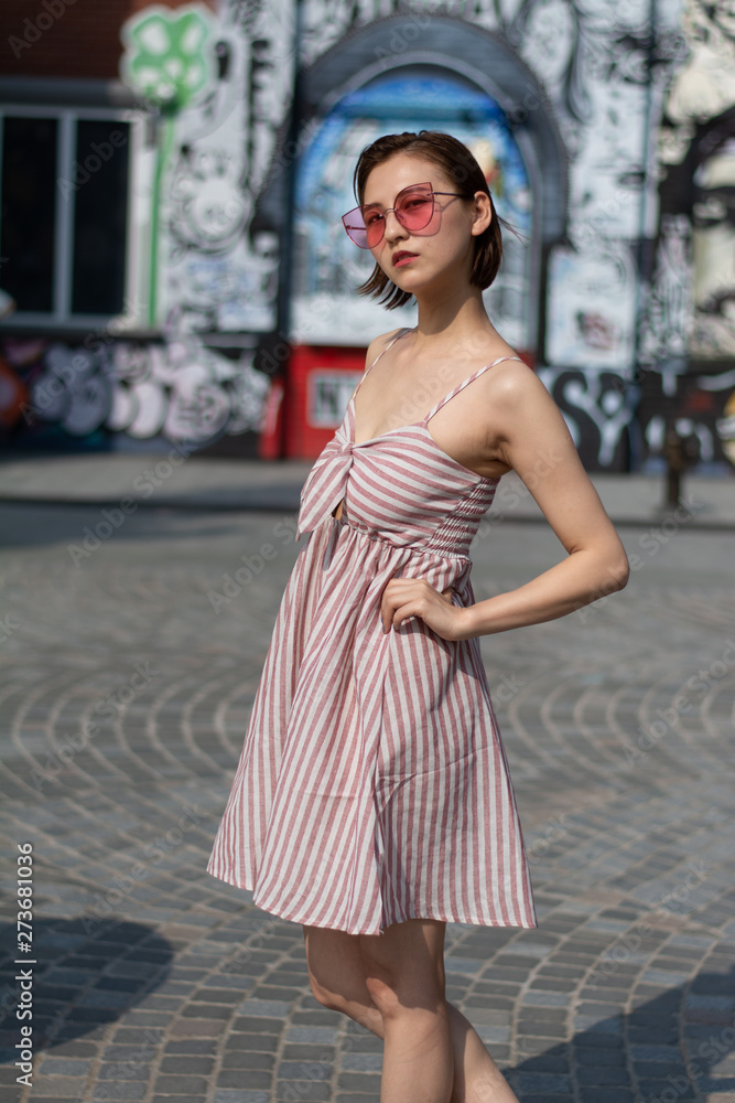 Asian Chinese model girl influencer street shot. Wearing pink dress and red shoes. Street Graffiti background. Asian Chinese model girl influencer street shot. Wearing pink dress and red shoes. Street Graffiti background.