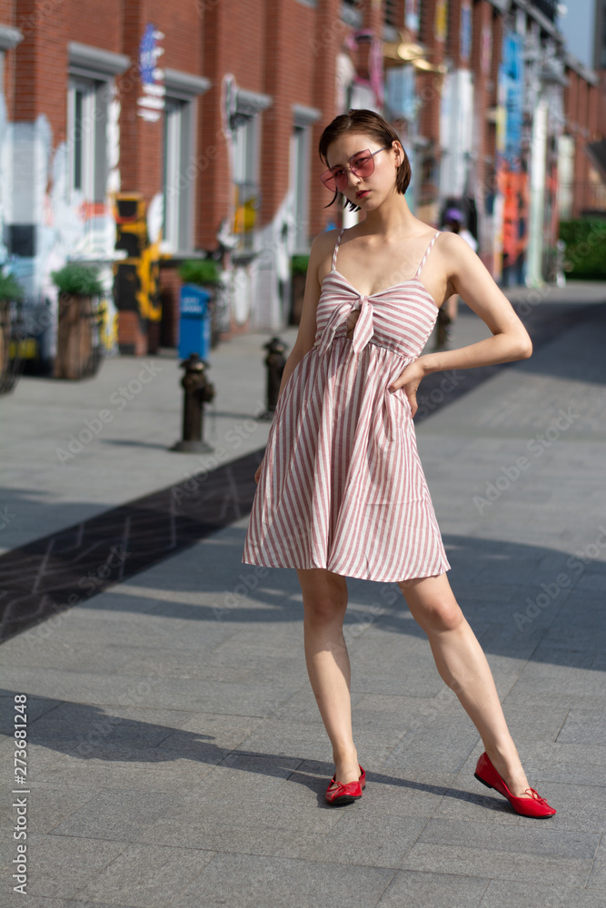Asian Chinese model girl influencer street shot. Wearing pink dress and red shoes. Street Graffiti background. Asian Chinese model girl influencer street shot. Wearing pink dress and red shoes. Street Graffiti background.