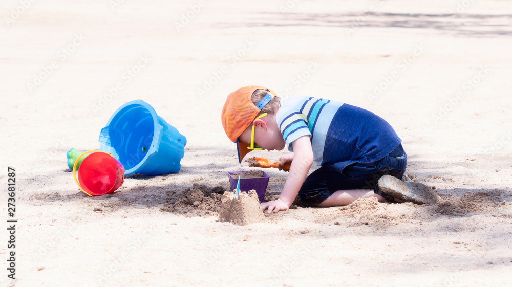 Toddler with Hat & Sunglasses Plays on a Sandy Beach with Buckets Building Sand Castles Toddler with Hat & Sunglasses Plays on a Sandy Beach with Buckets Building Sand Castles